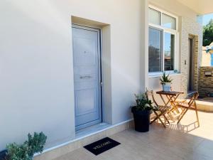 a front door of a house with a table and chairs at Nefele - Athens Airport Home in Artemida