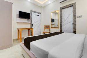 Un dormitorio con una cama blanca y un televisor. en Hotel O Shauryam, en Kankhal