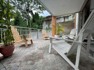 a porch with two wooden chairs and a table at Casa Arborizada - Bairro João Paulo Norte da ilha in Florianópolis