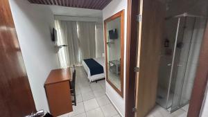 a room with a desk and a mirror and a room at Hotel Dourado in Alfenas