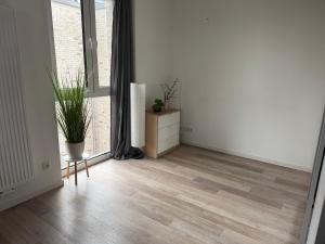 an empty room with a wooden floor and a plant at Ferienwohnung mit Balkon in Steinhagen in Steinhagen