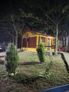 a yellow house with two bushes in front of it at Cabañas Sensaciones Serranas in Casa Grande