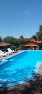 a large blue swimming pool with chairs and a house at Cabañas Sensaciones Serranas in Casa Grande