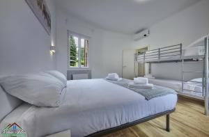 a white bedroom with a bed with white sheets at Casa Giuditta with Air Conditioning and Pool in Lierna