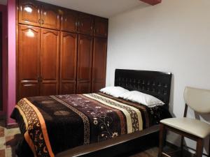 a bedroom with a bed with a wooden headboard and a chair at MJ Habitaciones Cholula in La Concepción