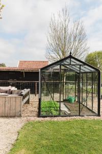 een zwarte kas in een tuin voor een gebouw bij Hof Driewegen in Driewegen