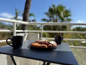 a table with two cups and a plate of pastries at Cozy Beachside Studio with Beach Access & Pool in Marigot