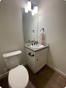 a bathroom with a toilet and a sink with a mirror at Home at Kingwood in Forest Grove in Forest Grove