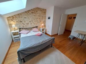 Saint-GoursonにあるLa grange Marieのベッドと石の壁のある寝室