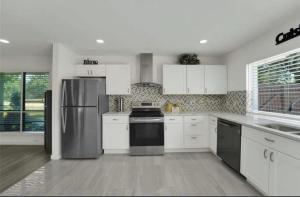 a kitchen with white cabinets and a stainless steel refrigerator at Spacious 3BR Oasis Pool Fire Pit & Family Fun in Cowley