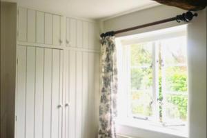 ein Fenster in einem Zimmer mit einem Vorhang in der Unterkunft Mews Cottage off Marlborough High Street in Marlborough