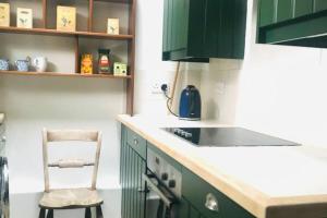 eine Küche mit grünen Schränken und einem Stuhl darin in der Unterkunft Mews Cottage off Marlborough High Street in Marlborough