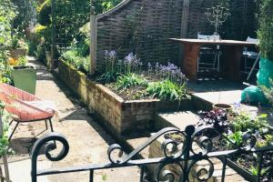 einen Garten mit einer Bank, einem Tisch und Blumen in der Unterkunft Mews Cottage off Marlborough High Street in Marlborough