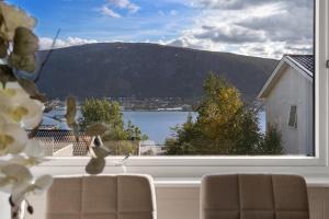 une fenêtre avec vue sur un lac et une montagne dans l'établissement Basecamp Dramsvegen Aurora Viewpoint, à Tromsø
