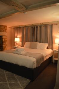 a bedroom with a large bed with curtains and lamps at The Red lion in Gloucestershire