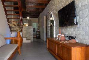 ein Wohnzimmer mit einem Fernseher an einer Steinwand in der Unterkunft Casa Hygge - Conforto, estilo e momentos únicos! in Tamandaré