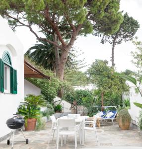 Un patio con sillas blancas y una mesa y un árbol. en Villa Michela, 2BR, 2BT, patio, newly renovated, en Capri