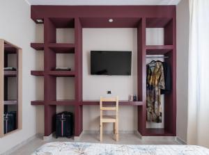 a room with a tv and a shelf with a chair at Bergamo Luxury apartment - Orange Blossom in Osio Sotto