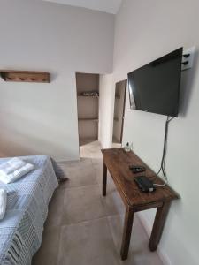 チラデンテスにあるPouso dos Arcanjosのベッド、テーブル、テレビが備わる客室です。