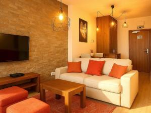 a living room with a white couch with orange pillows at Apartmán Sivý vlk Hrebienok Rezort in Smokovce