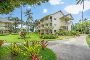 a large white building with palm trees and a driveway at Islander on the Beach 370 in Kapaa
