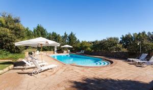 une piscine avec deux chaises et un parasol dans l'établissement ISA - Residence with swimming pool a few minutes from Alghero, à Santa Maria la Palma