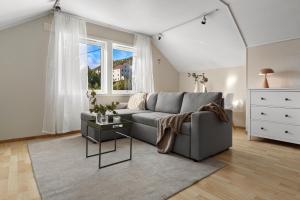 a living room with a gray couch and a window at Basecamp Dramsvegen Aurora Viewpoint in Tromsø +26 photos