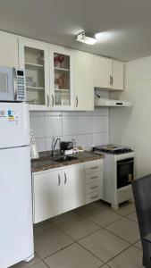 cocina con armarios blancos, fregadero y nevera en Apartamento Vista Mar - Beira Mar, en Fortaleza