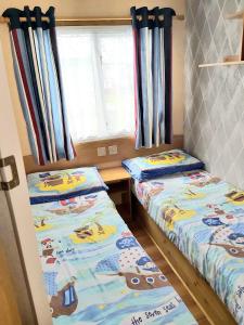 スケッグネスにあるE12 jeans caravan The Chaseの窓のある小さな部屋にベッドが2つある