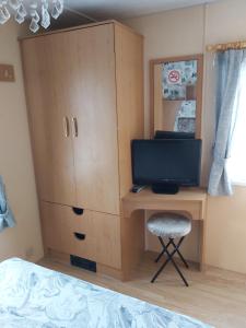 スケッグネスにあるE12 jeans caravan The Chaseのベッドルーム(デスク、テレビ付)、キャビネットが備わります。