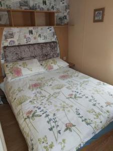 スケッグネスにあるE12 jeans caravan The Chaseの花柄のベッドカバーが備わるベッドルームのベッド1台分です。 +6枚の写真