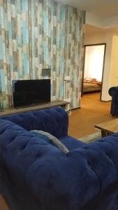 a living room with a blue couch and a flat screen tv at Afzal real estate builder's in Islamabad
