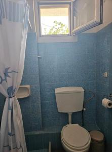 a blue bathroom with a toilet and a window at Aghia Marina, Aegina Studio in Aegina Town