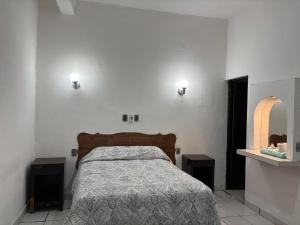 a bedroom with a bed and two lights on the wall at Habitaciones Climar in Veracruz