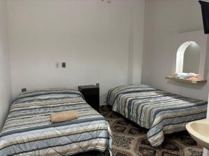 two beds in a room with a sink and a mirror at Habitaciones Climar in Veracruz