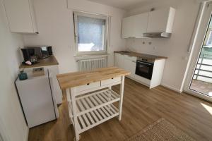 een keuken met witte kasten en een houten aanrechtblad bij Moderne Zimmer in Steinhagen mit Balkon in Steinhagen +4 foto's