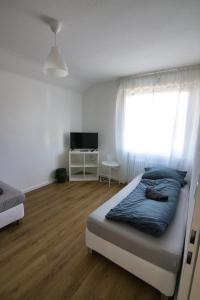 een slaapkamer met een bed, een raam en een televisie bij Moderne Zimmer in Steinhagen mit Balkon in Steinhagen