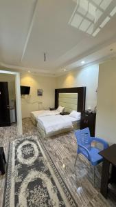 a bedroom with a large bed and a blue chair at نزل الصيف للشقق المخدومة in Al Namas
