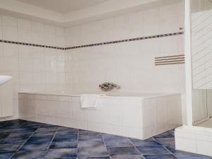 a white tiled bathroom with a tub and a shower at Apartment in Uitgeest by the Waterpark in Uitgeest +32 photos