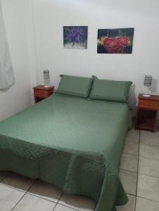 a bedroom with a bed with green sheets and two night stands at Casita de Arena Cabañas in Mar de Ajó