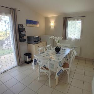 Un comedor con una mesa y sillas blancas. en Maison dans résidence mer - piscine, en Loc-Maria-Plouzané