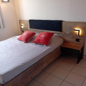 Un dormitorio con una cama con dos almohadas rojas. en Maison dans résidence mer - piscine, en Loc-Maria-Plouzané