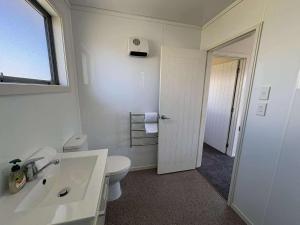 a white bathroom with a toilet and a sink at Braeview Cottage in Lake Tekapo +7 photos