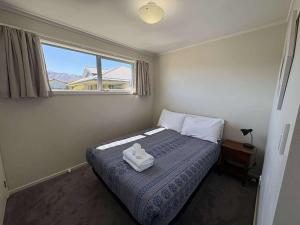a bedroom with a bed with two towels on it at Braeview Cottage in Lake Tekapo