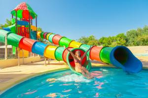 バラリュック・レ・バンにあるCamping Mas du Padreの若い女の子がウォーターパークのウォータースライダーを滑り降りている