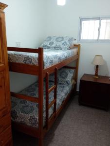 two bunk beds in a room with a table at Casita de Arena Cabaña 1 in Mar de Ajó