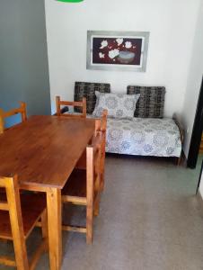 a dining room with a wooden table and a couch at Casita de Arena Cabaña 1 in Mar de Ajó