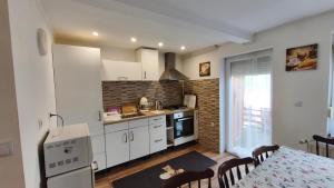 a kitchen with white cabinets and a table with a dining room at Rigófészek Apartmanház in Gárdony