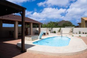 a pool with a water slide in a backyard at LiCe Garden Aruba in Paradera
