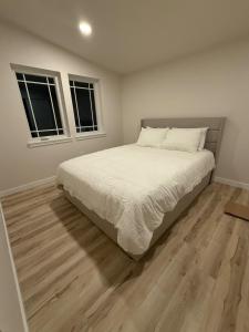 a bedroom with a bed with white sheets and two windows at North Slope Nest in Tacoma